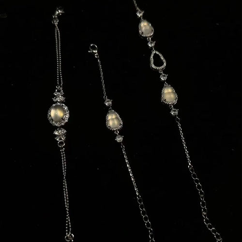 Three elegant silver bracelets adorned with glowing moonstone-like gems (featuring gourd and teardrop shapes) and sparkling crystals, displayed against a dark backdrop — ideal as a complimentary gift.