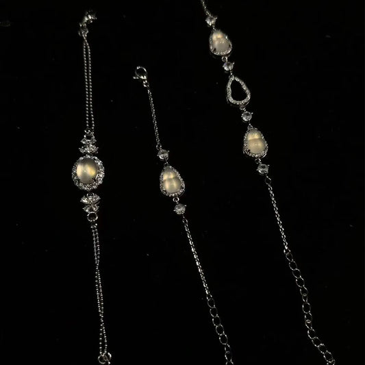 Three elegant silver bracelets adorned with glowing moonstone-like gems (featuring gourd and teardrop shapes) and sparkling crystals, displayed against a dark backdrop — ideal as a complimentary gift.